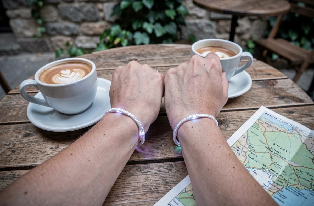 Deux bracelets connectés assortis posés sur une table de café en bois symbolisant une relation à distance