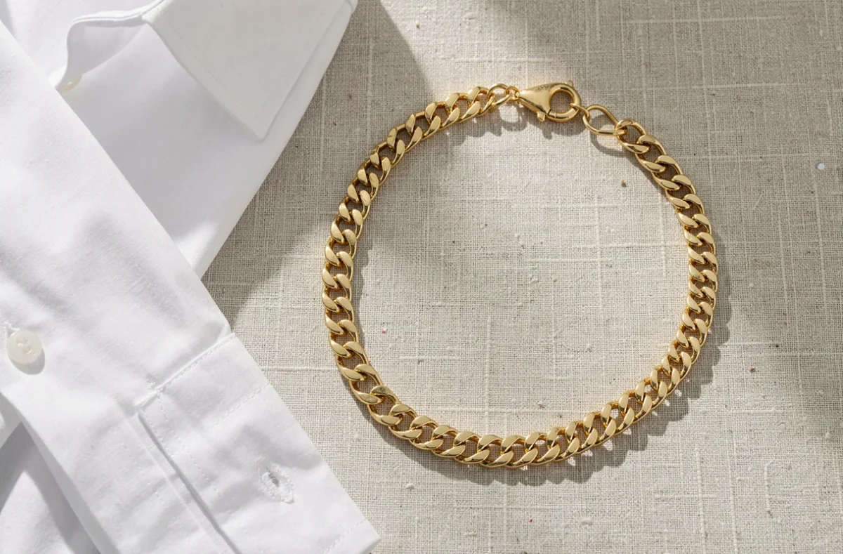 Collier à grosse maille dorée posé sur du lin clair